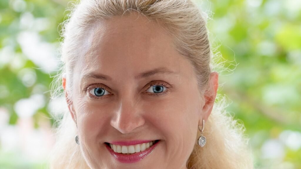 A smiling blonde woman with fine lines at the corners of her blue eyes