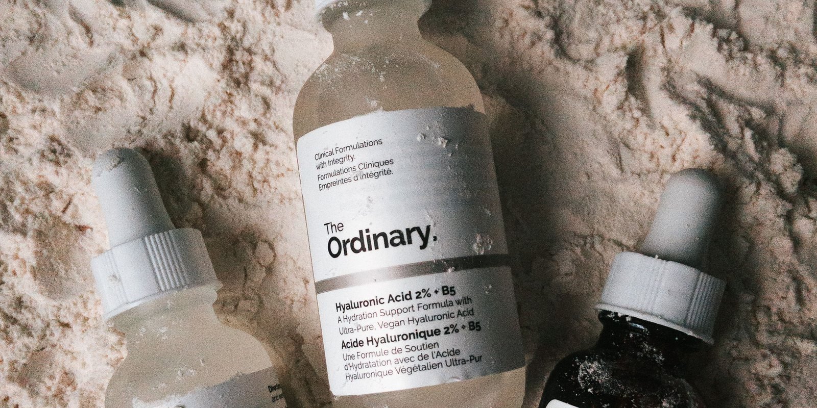 Three serum bottles lying half-buried in pale sand