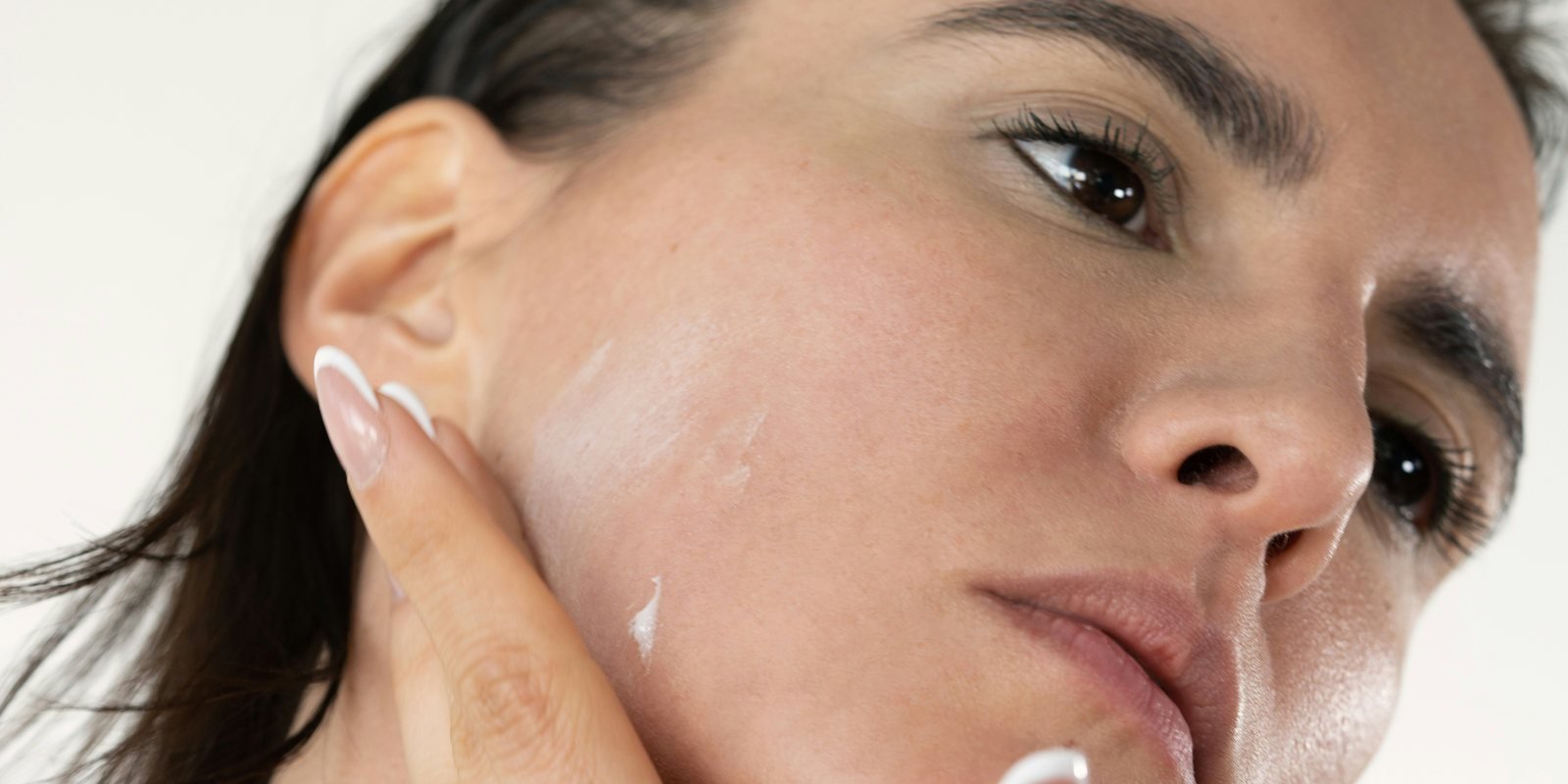A woman smoothing moisturizer along her jaw and cheek